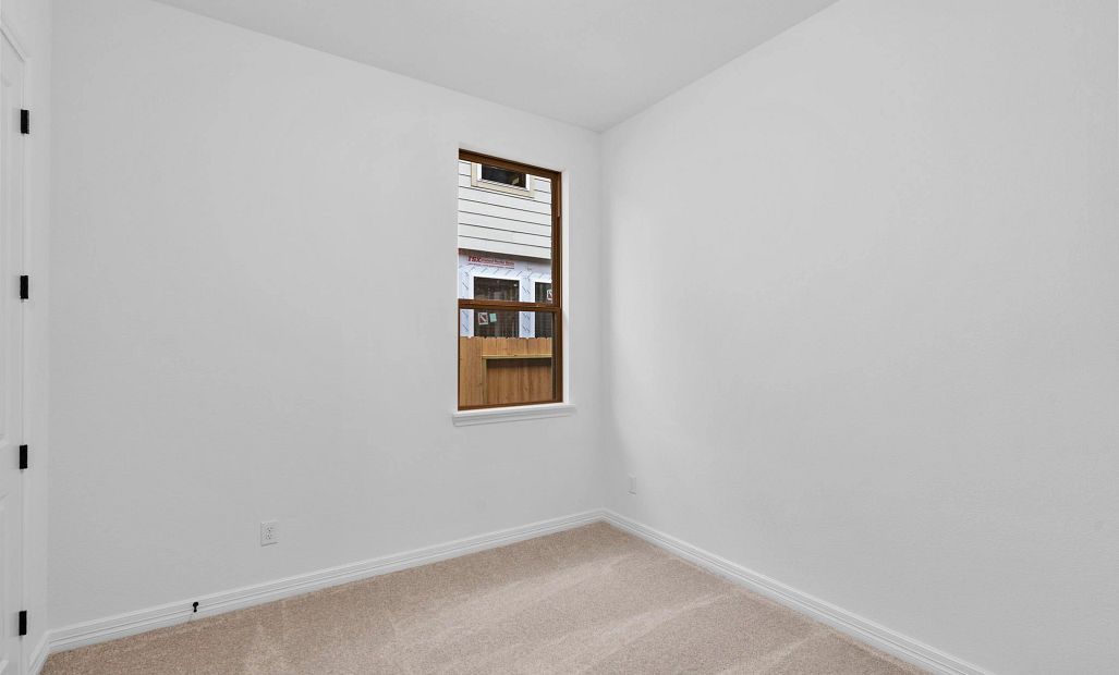 A comfortable third bedroom with plush carpet, a sun-filled window, and ample closet space.