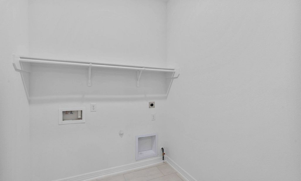 Functional utility room with custom shelving and convenient laundry hookups.