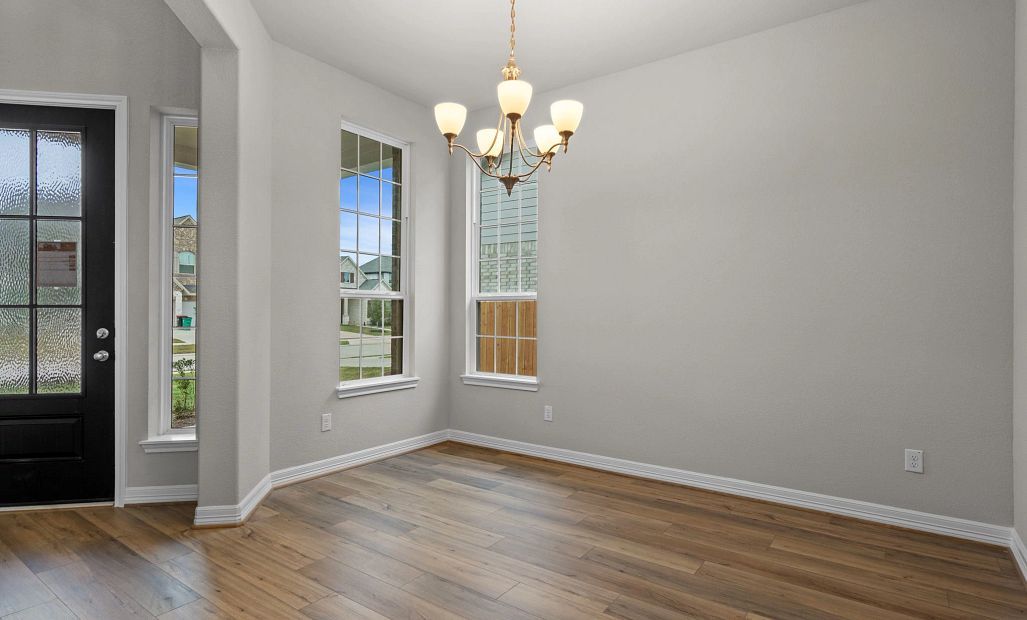 Elegant formal dining room with chandelier and large windows, seamlessly connected to the kitchen