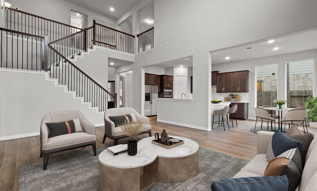 Stunning open-concept living space featuring a double-story family room, grand staircase, and