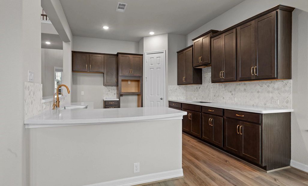 Well-designed kitchen featuring a walk-in pantry, generous counter space, dark cabinets, white