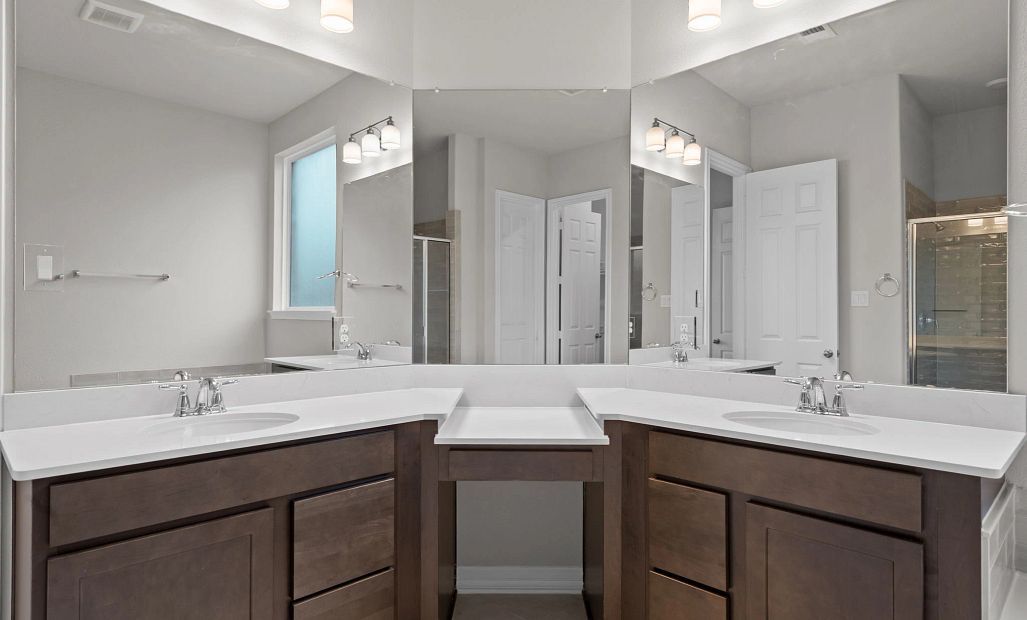 Luxurious primary bath featuring a double-sink vanity with makeup counter, dark-stained cabinets,