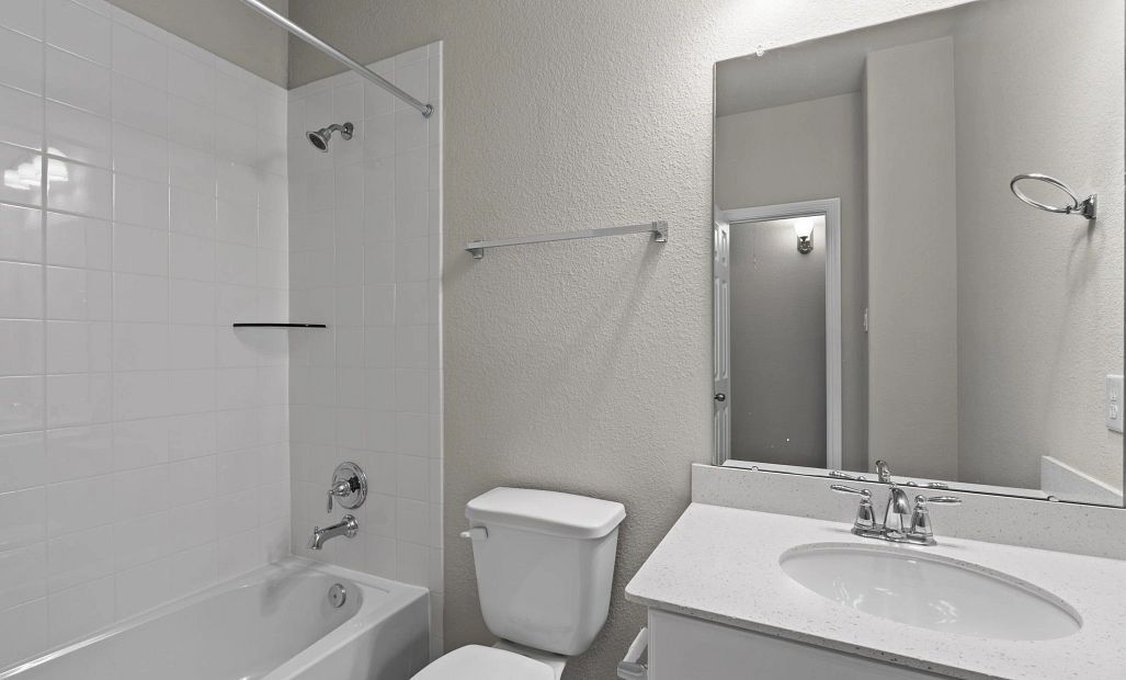 Bright third bath featuring white cabinetry, light surfaces, and a classic shower/tub with tile