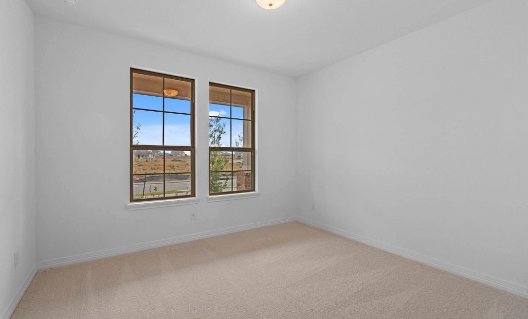 A bright and cozy fourth bedroom featuring plush carpet and sun-filled almond windows that add