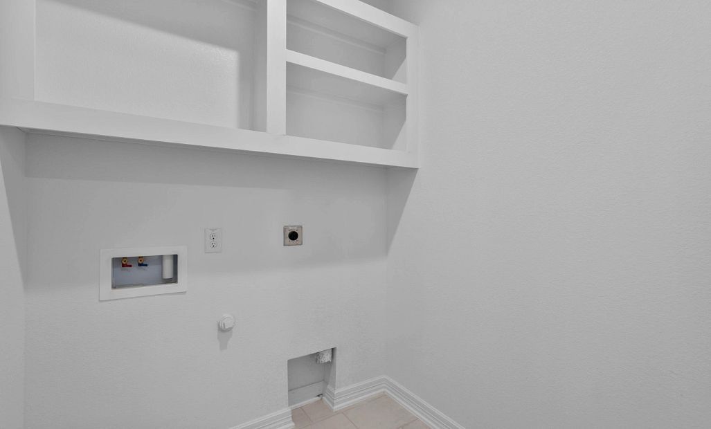 Functional utility room with shelving and convenient laundry hookups.