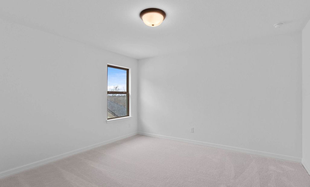 Additional bedroom upstairs with cozy carpet and a bright, airy window.