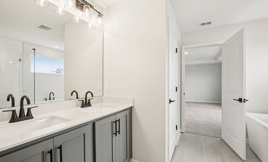 Primary bathroom with double sink and a free standing tub featuring AW Collection® Minimalist