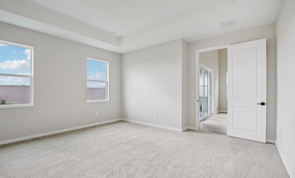 Primary suite located off the family room with double windows and a tray ceiling
