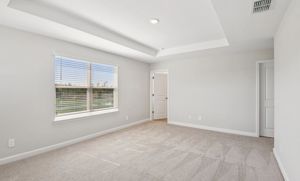 Spacious primary bedroom with a pond view
