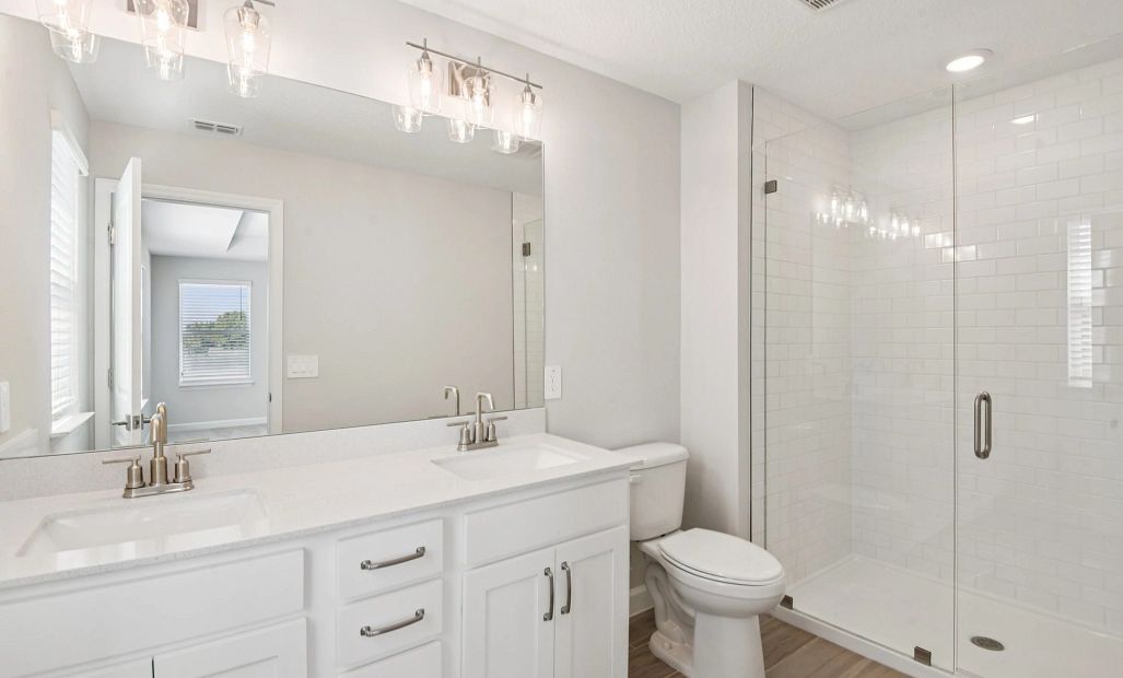 Beautiful primary bathroom with double sinks and a large frameless walk-in shower all with aspects