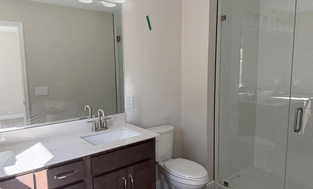 Primary bathroom featuring aspects of AW Collection® Roosevelt, double sinks and a frameless walk-in