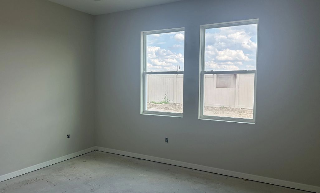 Primary bedroom located off the back of the home with double windows and a tray ceiling - under