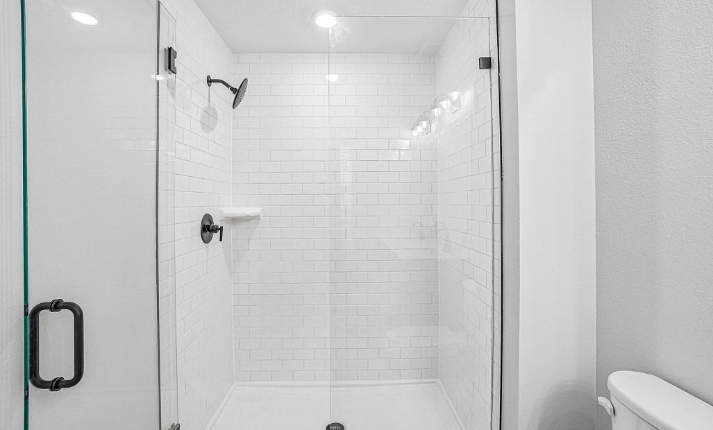 The primary bathroom features a frameless walk-in shower