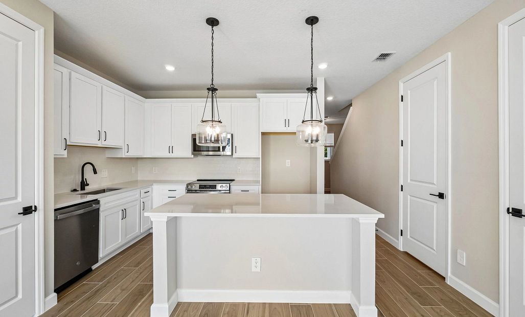 Kitchen with our AW Collection® Harmony has a large island and stainless steel microwave, dishwasher