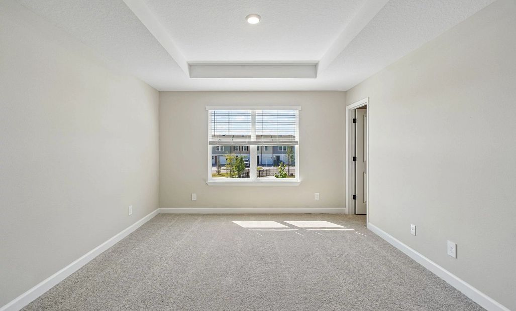 Primary bedroom with a tray ceiling and great natural light from the double window