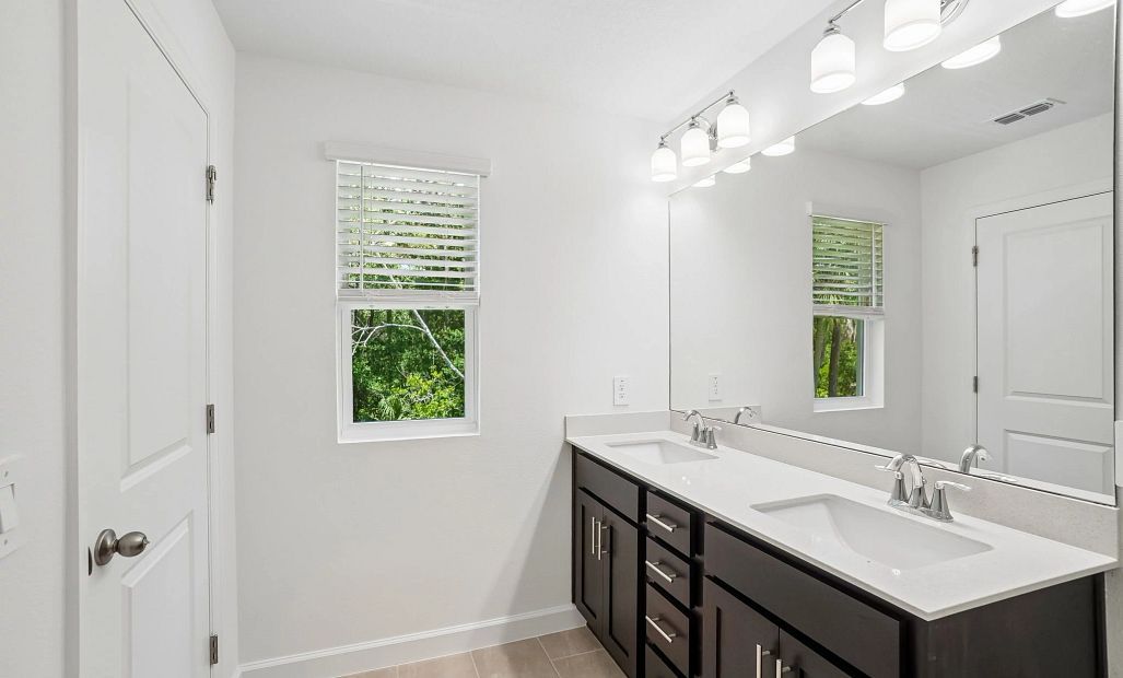 Primary bathroom features double sinks and a window for natural light