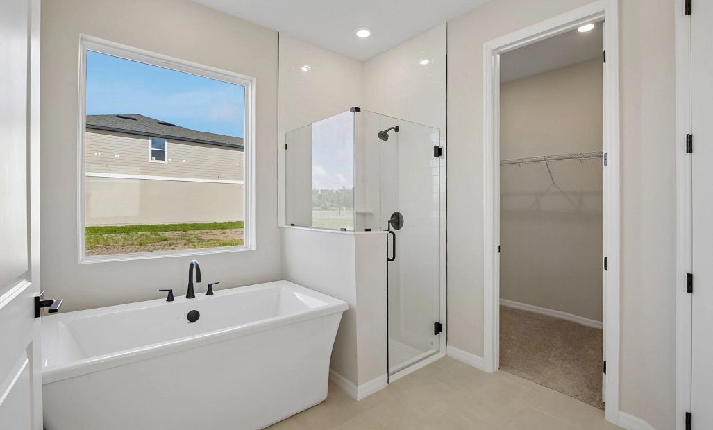 The primary bathroom features a free standing tub and a walk-in frameless shower