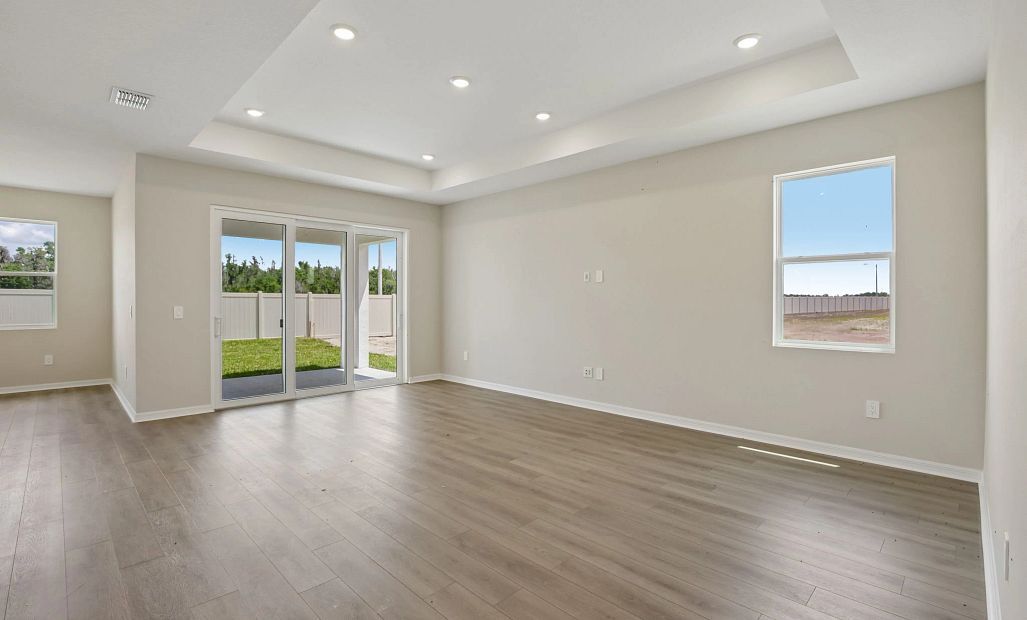 The spacious family room features a tray ceiling and looks out the large sliding glass door