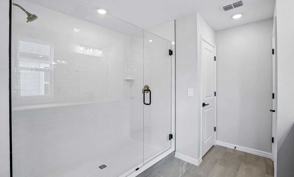The primary bathroom has an oversized frameless walk-in shower