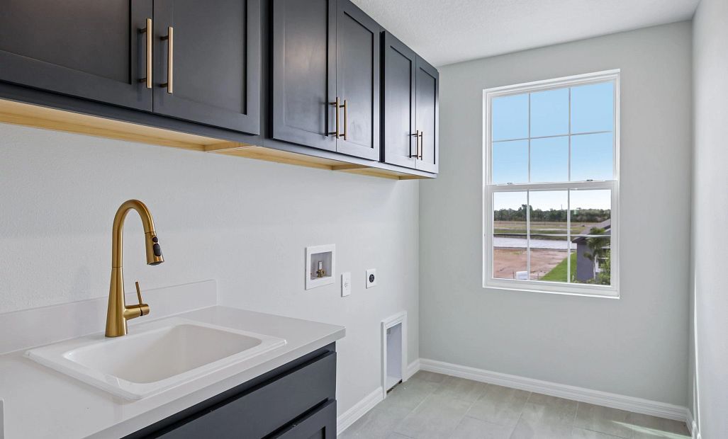 The laundry room features upper cabinets and a laundry sink all outfitted in our AW Collection®