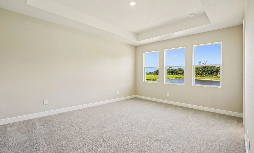In the back of the home is primary suite featuring three large windows looking out at the pond view