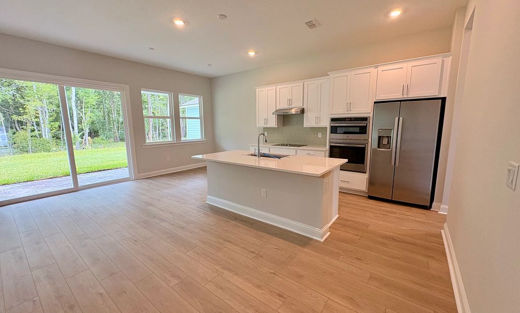 Spacious kitchen with large island, double stack oven and microwave and a cooktop with vent hood