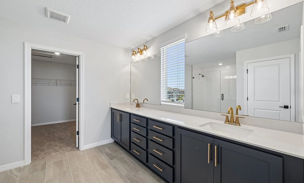 The primary bathroom features a window and double sinks and includes aspects of AW Collection®