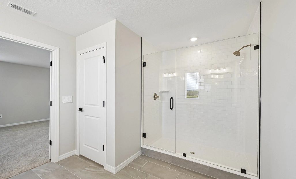 The primary bathroom features a large walk-in frameless shower