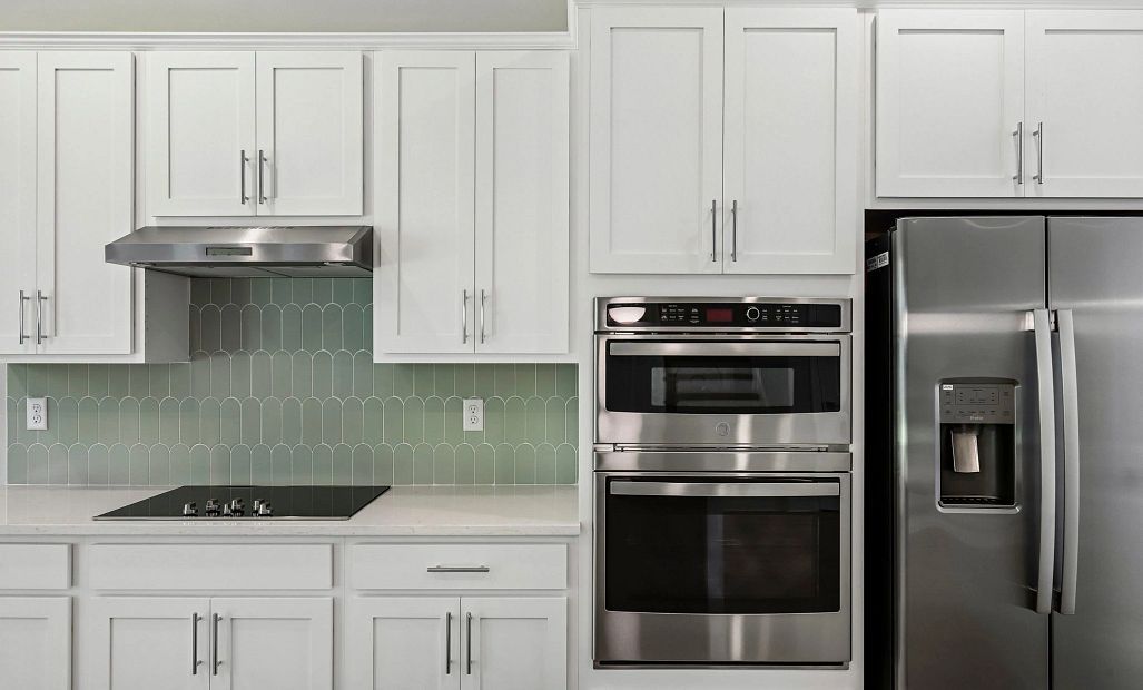 The kitchen has a vent hood and flat range, a double stack wall microwave and oven and a