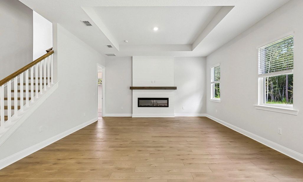 Beautiful family room features a tray ceiling and a built-in fireplace with a wood mantel