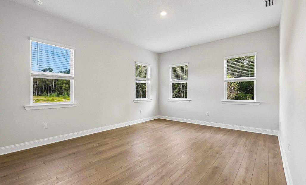 Spacious primary bedroom with four large windows providing great natural light