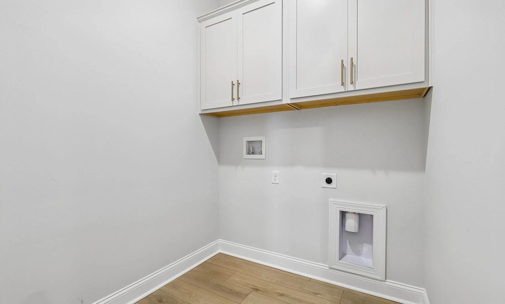 Laundry room features upper cabinets providing extra storage space