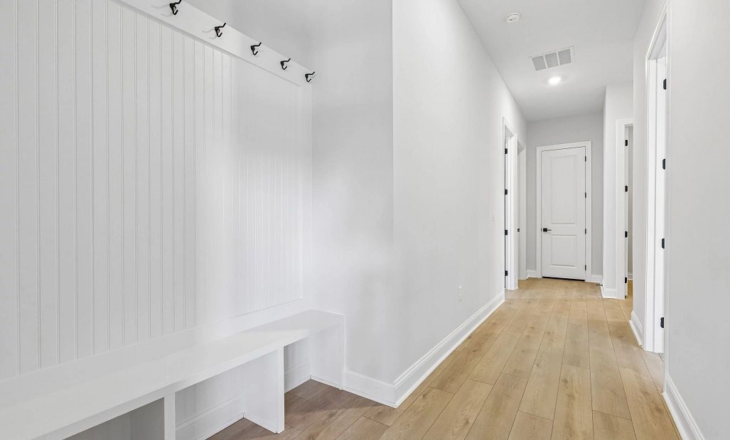 Hallway off the garage features a valet with built-in bench and hooks