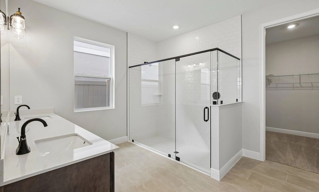 The primary bathroom has a large frameless walk-in shower