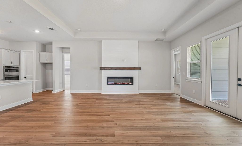 The kitchen opens up into the living room, which features a stunning fireplace with a wood mantle