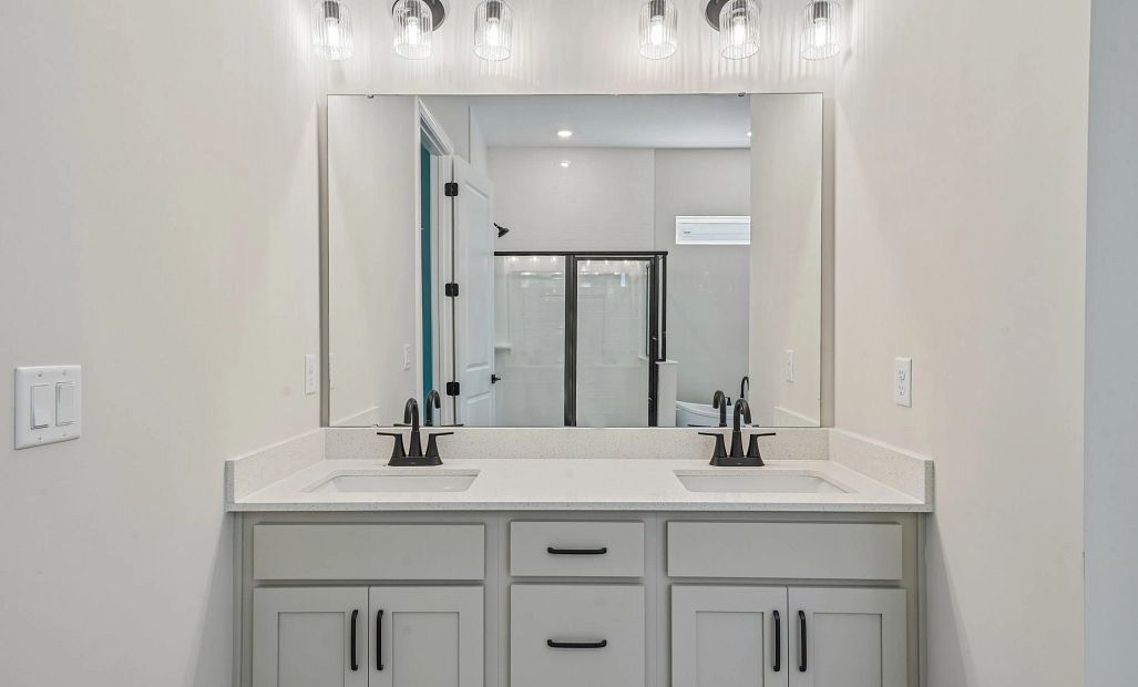 The primary bathroom has a double vanity and features aspects of AW Collection® Harmony