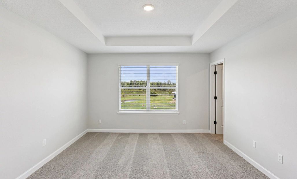 Spacious primary bedroom with a tray ceiling -  Representative images and renderings are for
