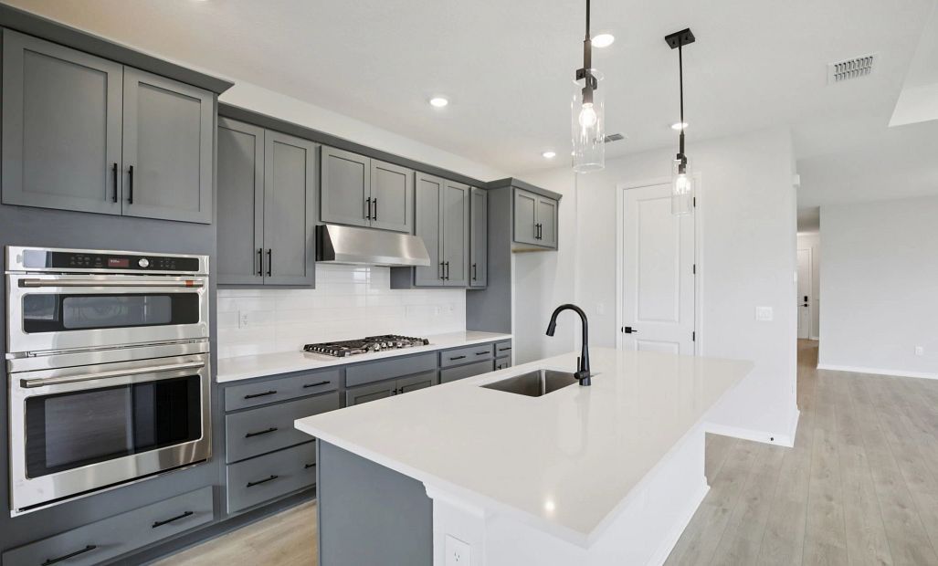 The kitchen features a stacked oven and microwave, flat top range and a vent hood the kitchen will