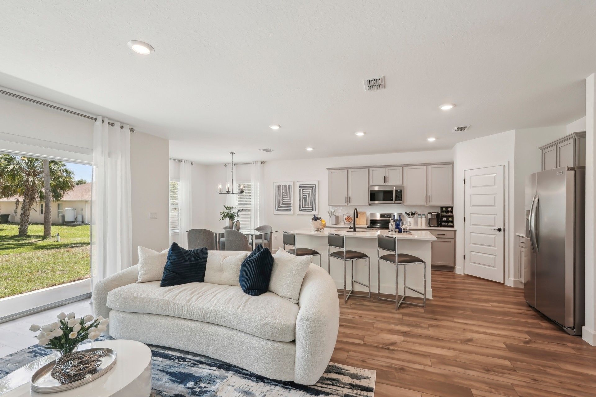 Sleek kitchen with gray cabinets and island opens to a chic living area in North Port.