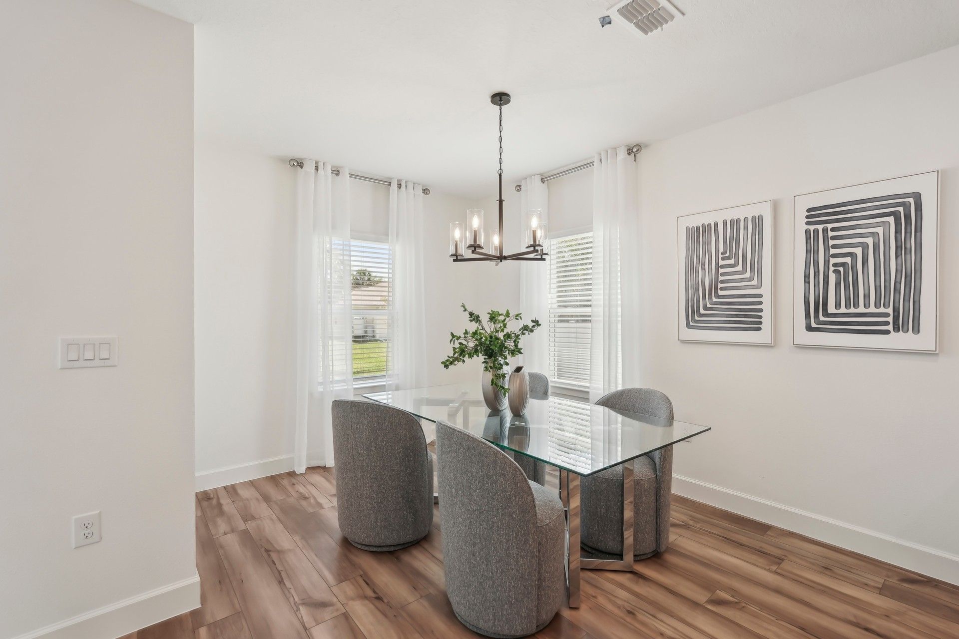 Elegant North Port dining room boasts a glass table, chic lighting, and stylish art.