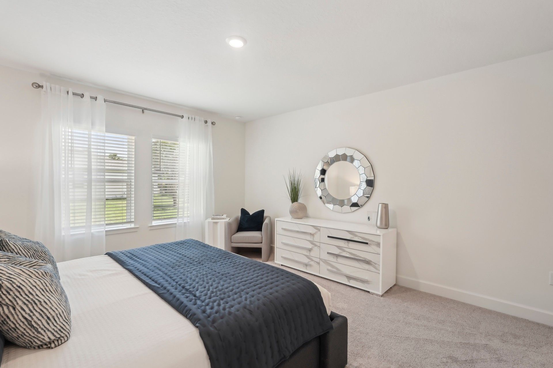 Elegant North Port bedroom with a chic round mirror and contemporary white dresser.