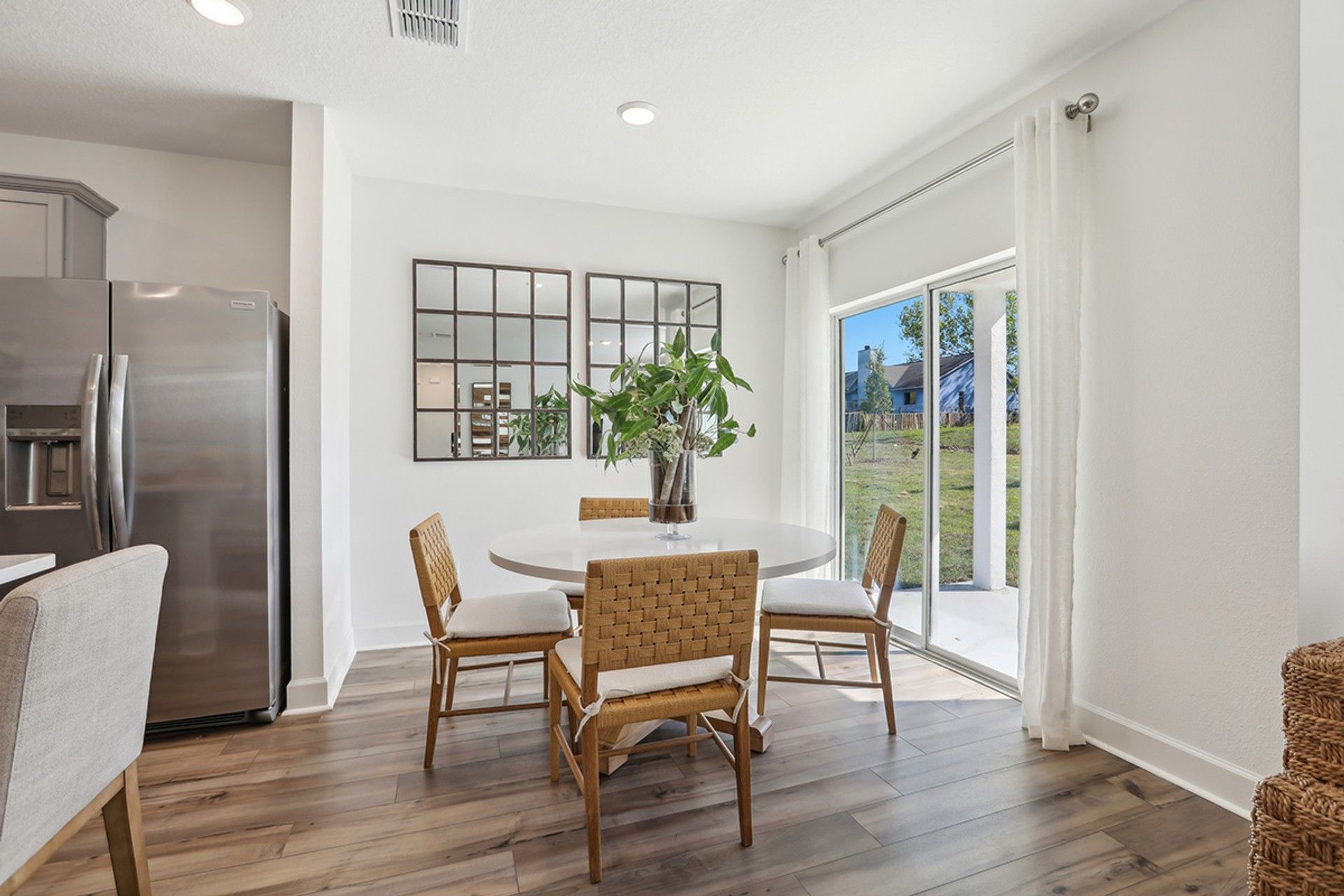 Spring Hill dining area boasts chic woven chairs and expansive glass doors for garden views.