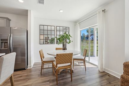 Spring Hill dining area boasts chic woven chairs and expansive glass doors for garden views.
