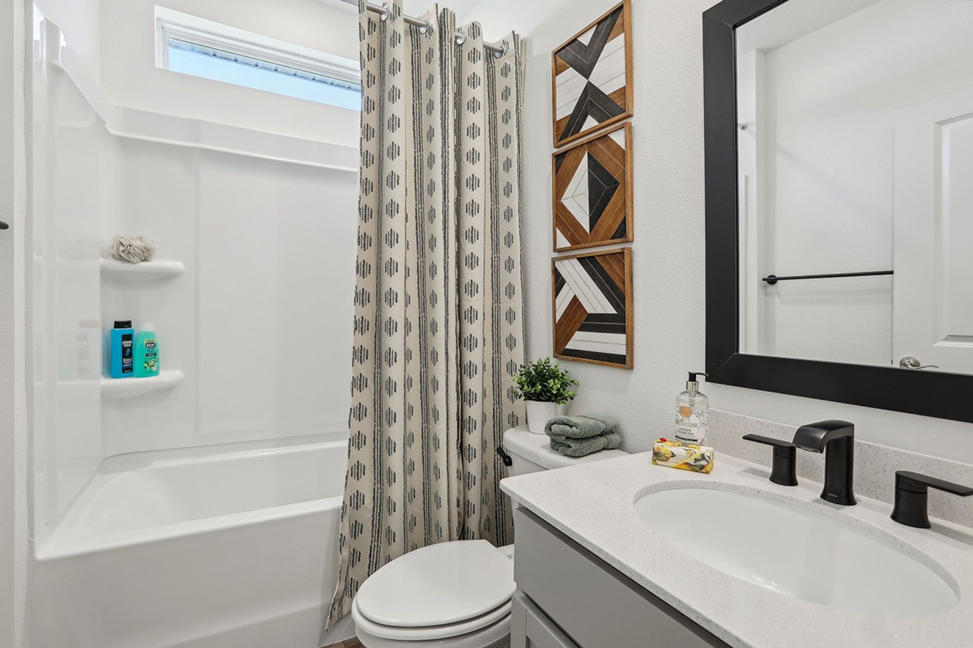 Sophisticated Spring Hill bathroom features sleek black fixtures and striking geometric wall art.