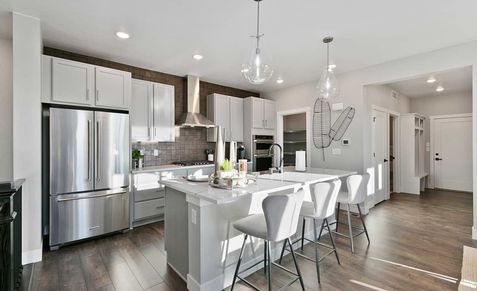 Elegant kitchen with quartz island, designer lighting, and premium stainless steel appliances. Trailside on Harmony.