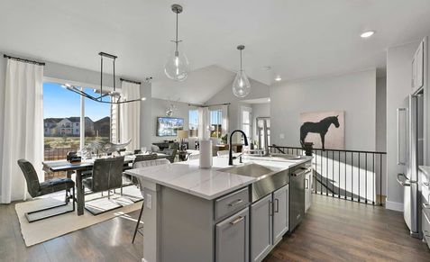Elegant kitchen with marble island, pendant lighting, and hardwood flooring in Trailside on Harmony, Colorado.