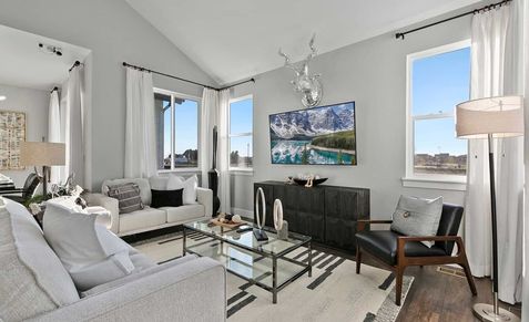 Discover elegant vaulted ceilings and sleek glass accents in Trailside on Harmony's refined living area.