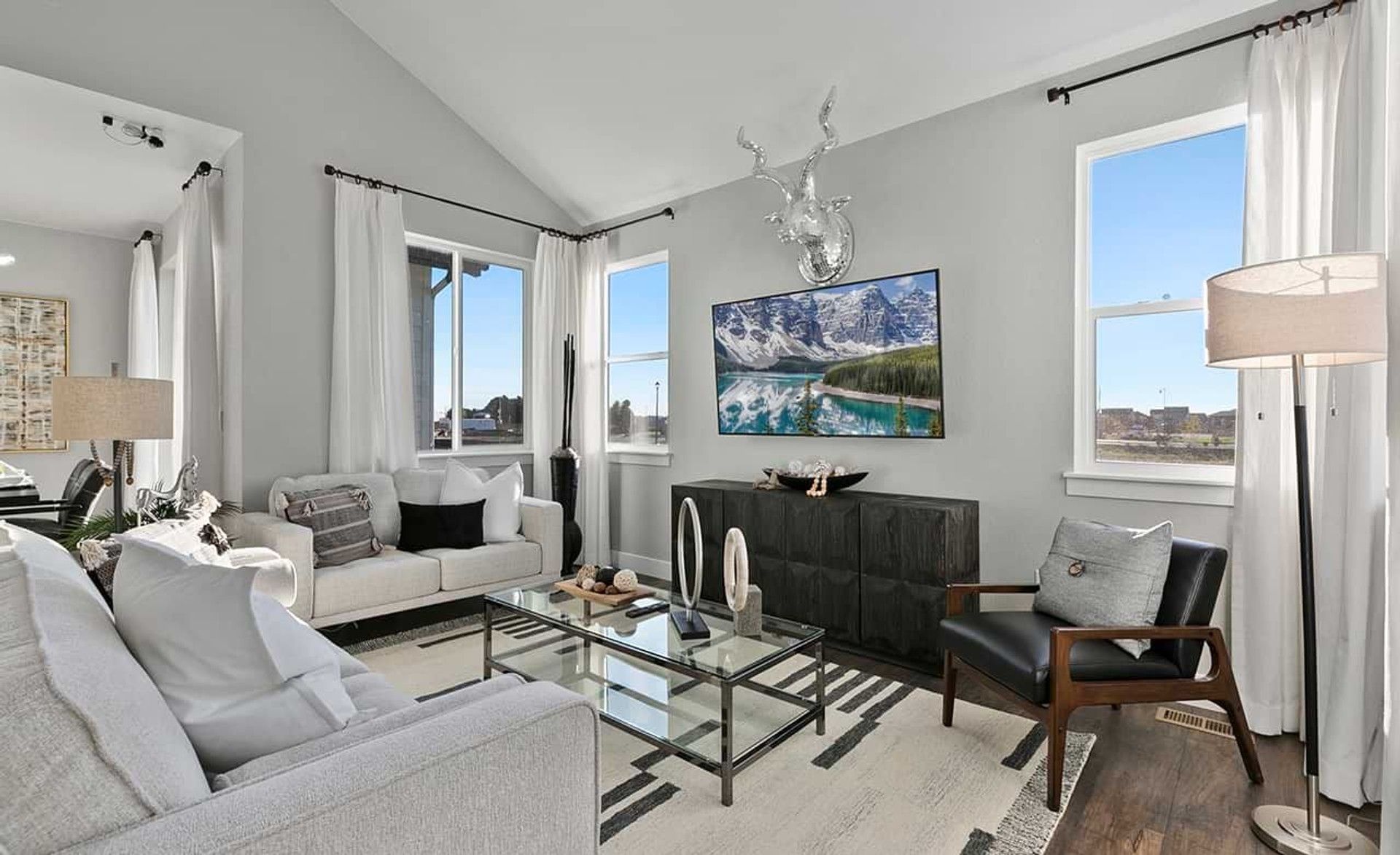 Discover elegant vaulted ceilings and sleek glass accents in Trailside on Harmony's refined living area.