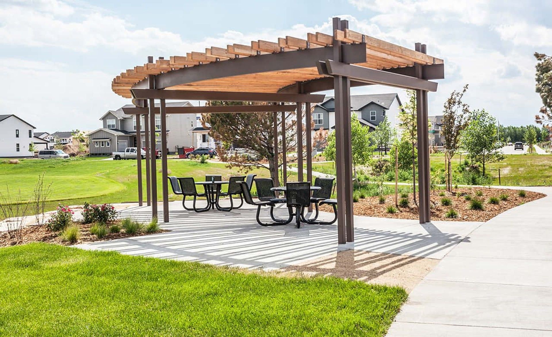 Sleek wooden pergola defines this elegant seating area in Trailside on Harmony, blending seamlessly with lush surroundings.