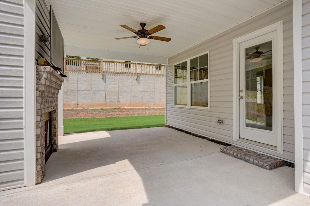 Exterior Back of Home.   View of Game Day Porch and outdoor brick fireplace. 10' x 12' Concrete Patio.  Ceiling Fan/Light and Hook up for TV. Low Maintenance Vinyl Siding.    Architectural Shingles and Aluminum Gutters.